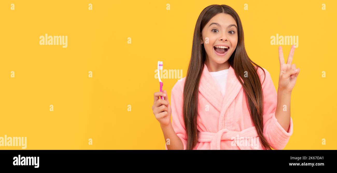 bonne surprise teen fille à la maison terry peignoir tenir brosse à dents montrer la paix geste, l'enfance. Bannière de l'enfant fille avec brosse à dents, portrait de studio Banque D'Images