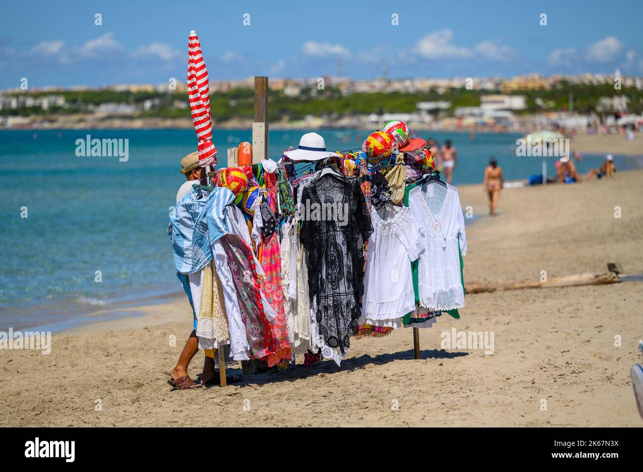 Un vendeur de plage avec son rack de marchandises à vendre sur la plage de Sottovento près de Gallipoli à Apulia (Puglia), Italie. Banque D'Images