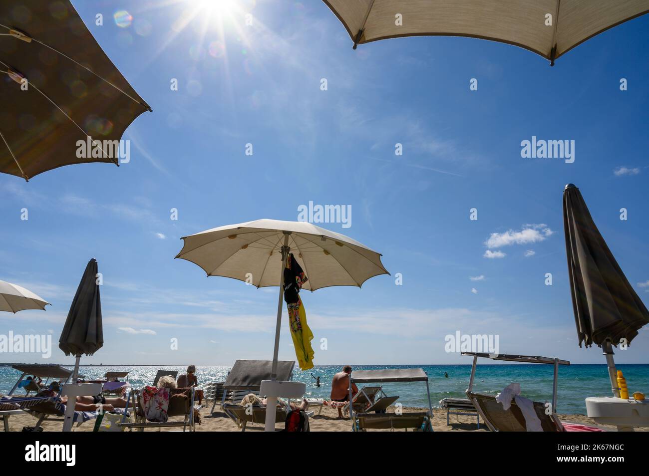 Bains de soleil et plage avec chaises longues et parasols sur la plage de Sottovento au sud de la ville de Gallipoli, Pouilles, Italie. Banque D'Images