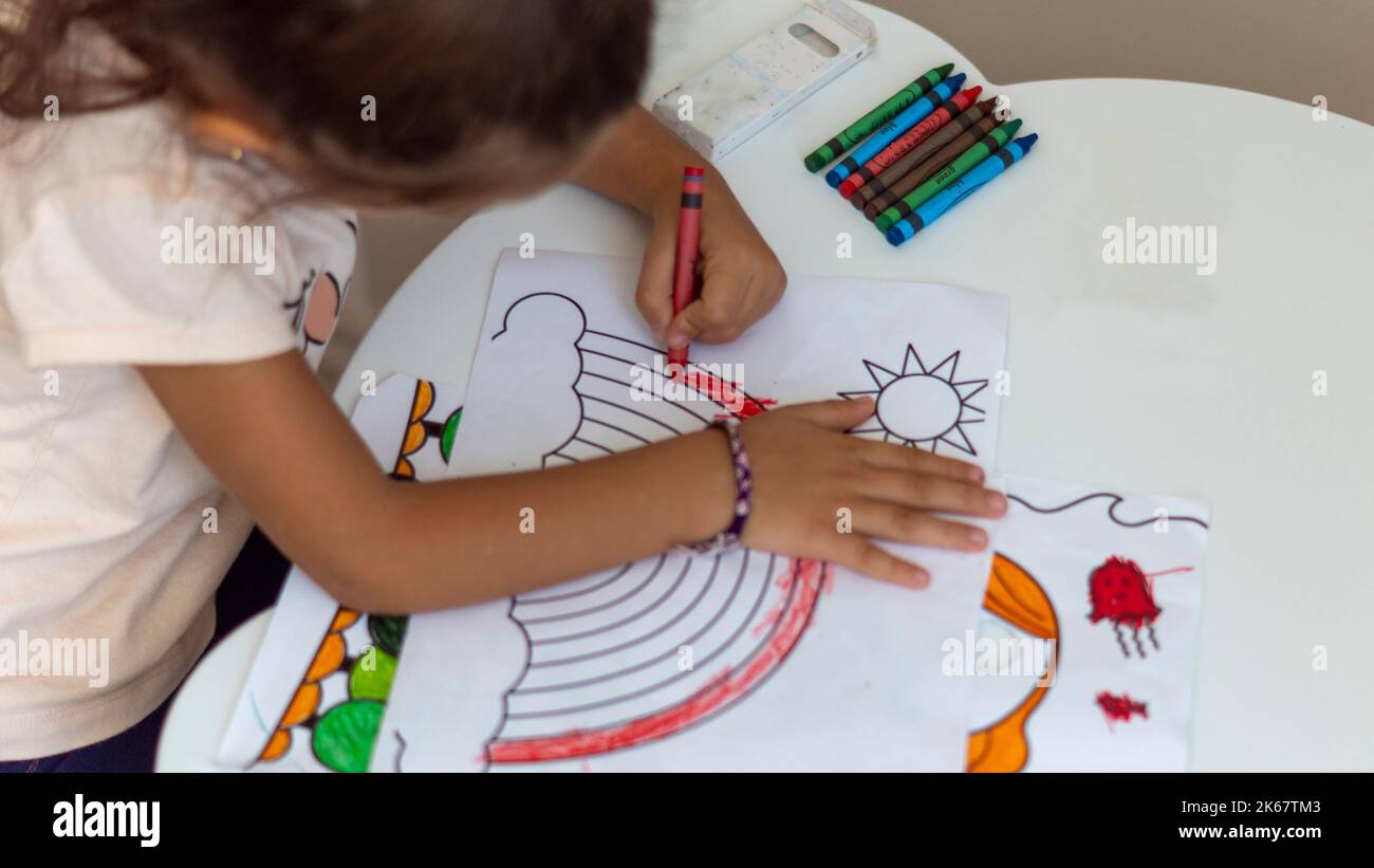 l'enfant peint. l'enfant peint l'arc-en-ciel dans la maternelle. La fille apprend à tenir un crayon et à peindre correctement à la maternelle. Activité amusante Banque D'Images
