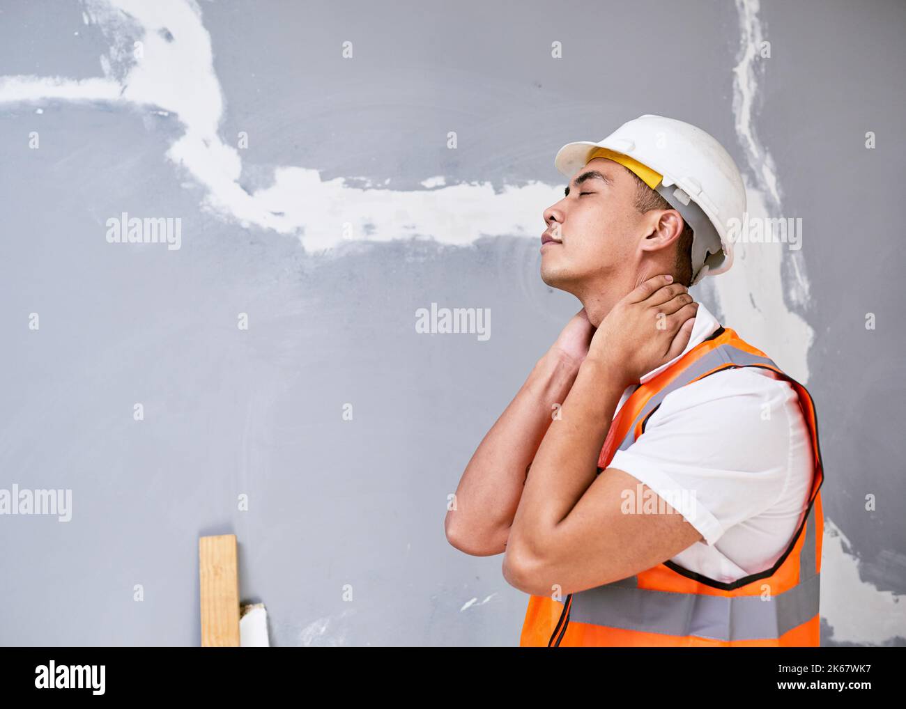 Un jeune ouvrier asiatique de la construction tient son cou dans la douleur de blessures de travail Banque D'Images