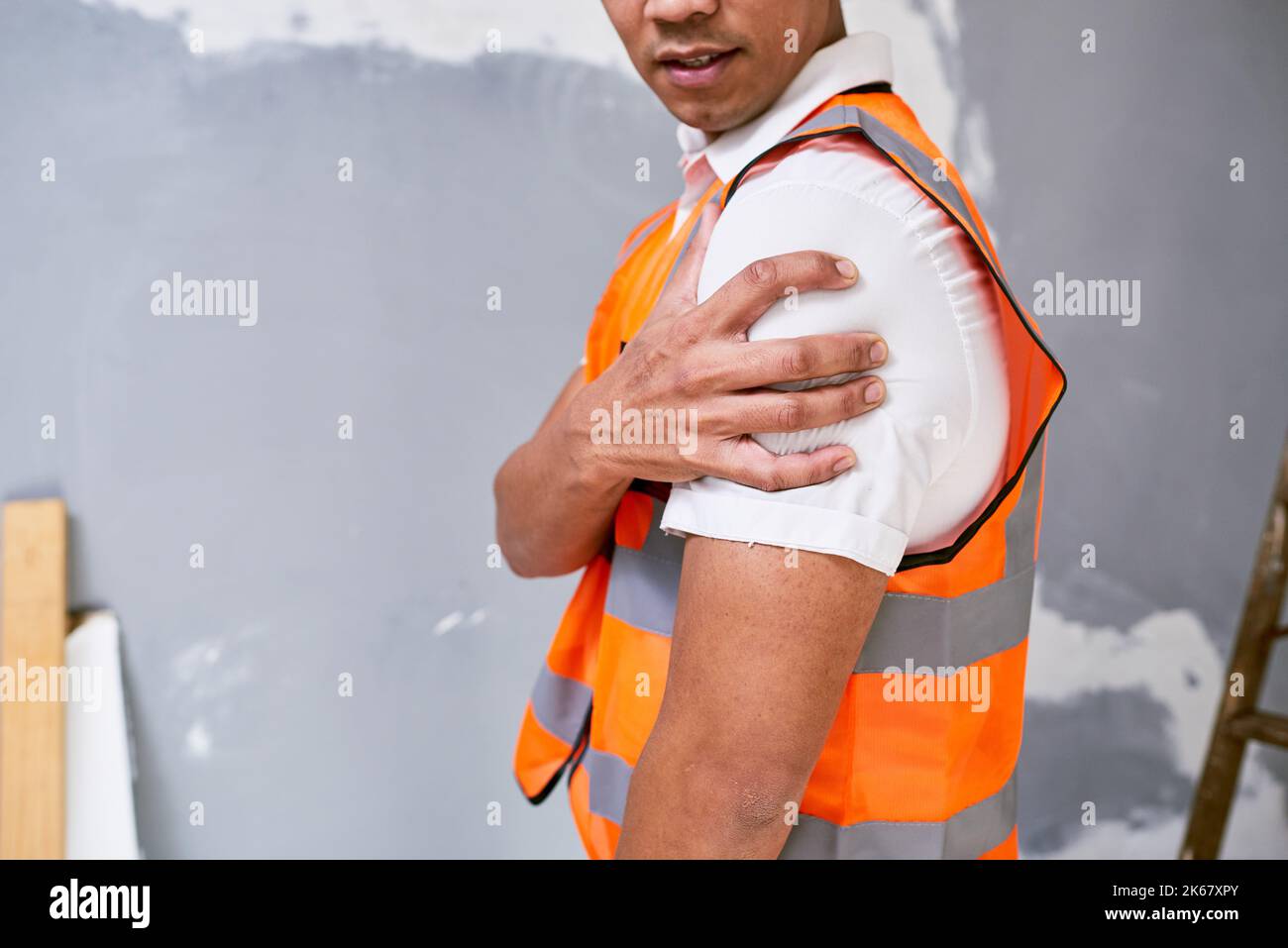 Le travailleur de la construction tient l'épaule dans la douleur résultant d'une blessure sur le lieu de travail sur le site Banque D'Images