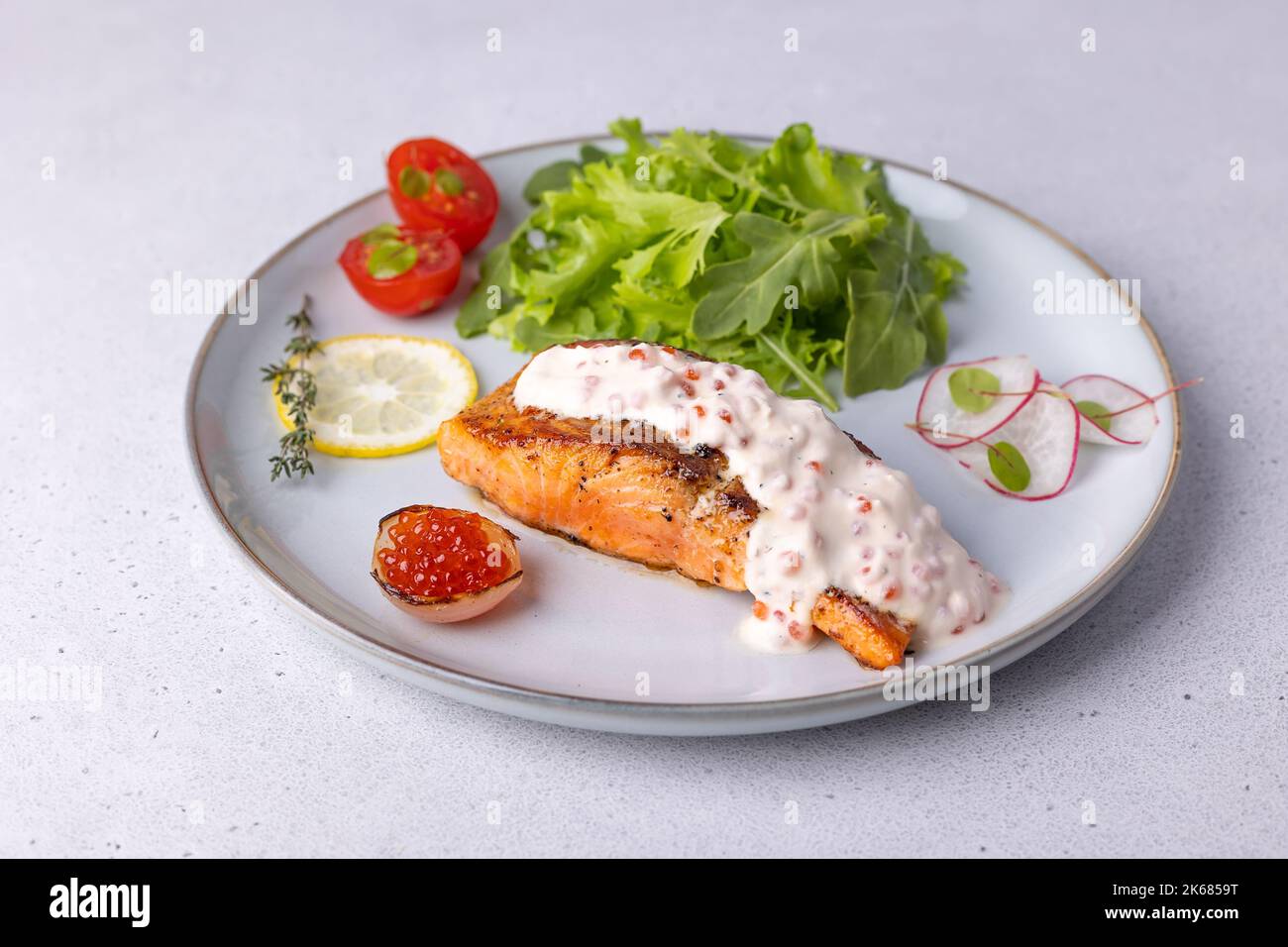 Saumon (truite) à la sauce crémeuse au champagne avec caviar rouge, arugula, tomates cerises, radis et citron. Plat français traditionnel. Mise au point sélective, clos Banque D'Images