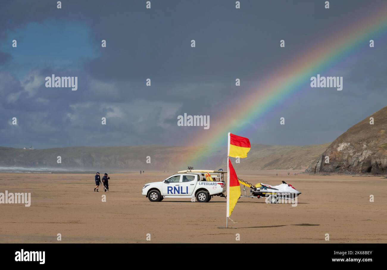 Un arc-en-ciel brillant sur un véhicule RNLI à Perranporth, en Cornouailles. Jet ski et drapeaux d'avertissement aussi Banque D'Images