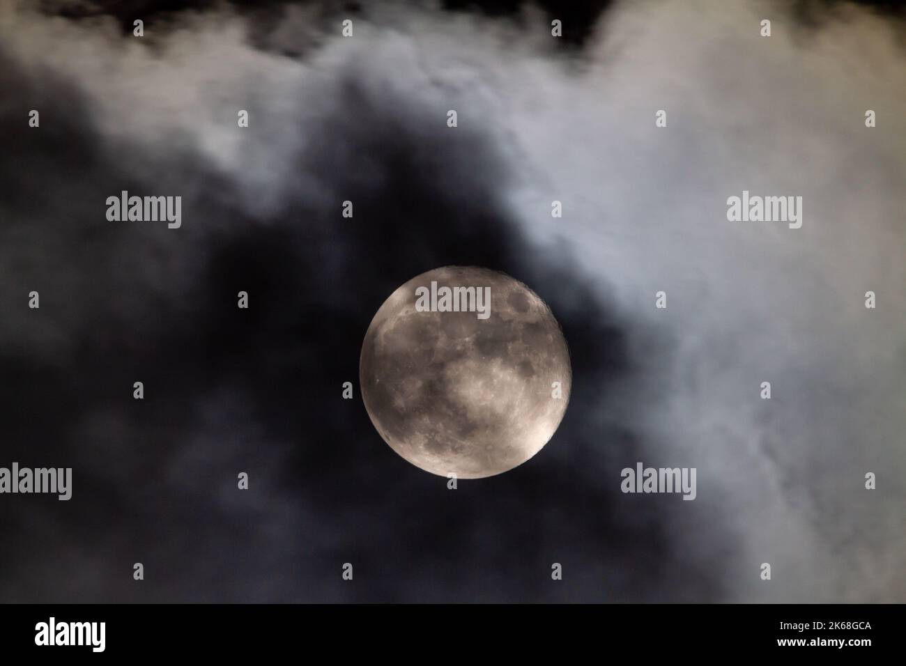 Des nuages inquiétants passent devant une pleine lune dans le ciel nocturne. Banque D'Images