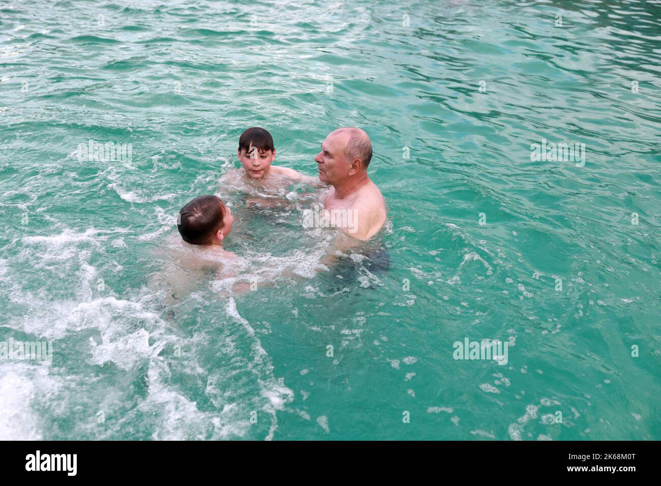 Grand-père et petits-fils nageant dans la piscine thermale chaude, Adygea Banque D'Images
