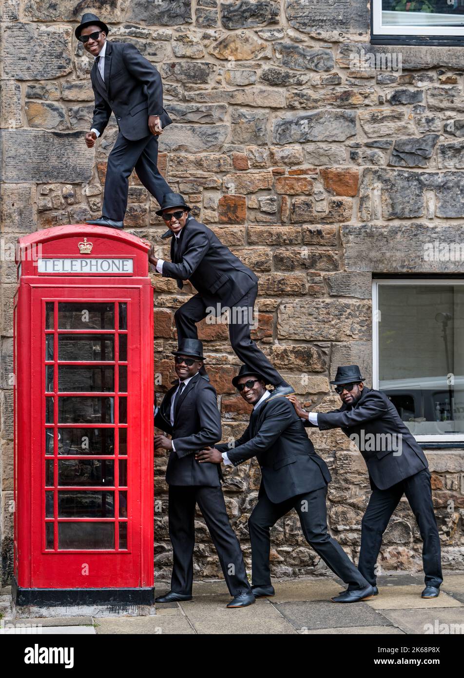 Le groupe acrobatique des Black Blues Brothers se présente à Dean Village par une boîte téléphonique rouge, à Édimbourg, en Écosse, au Royaume-Uni Banque D'Images