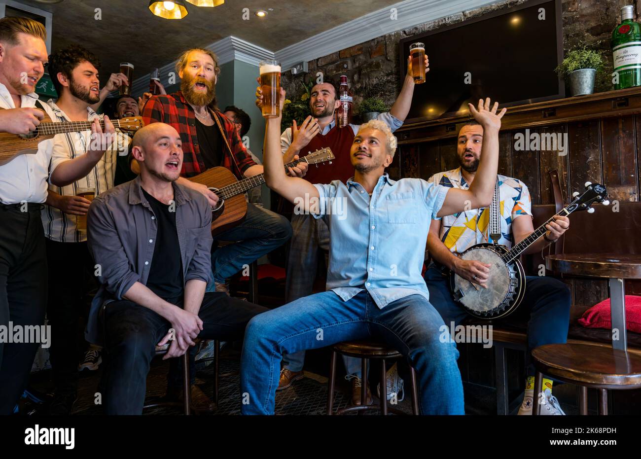 Choeur de groupe Man chantant, jouant de la musique et buvant de la bière dans un pub, Grassmarket, Édimbourg, Écosse, Royaume-Uni Banque D'Images