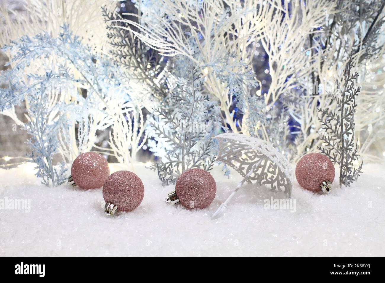 Les jouets de Noël se trouvent sur la neige artificielle sur fond d'arbres artificiels bleus et blancs. Gros plan. Prise de vue en studio de nuit. Banque D'Images