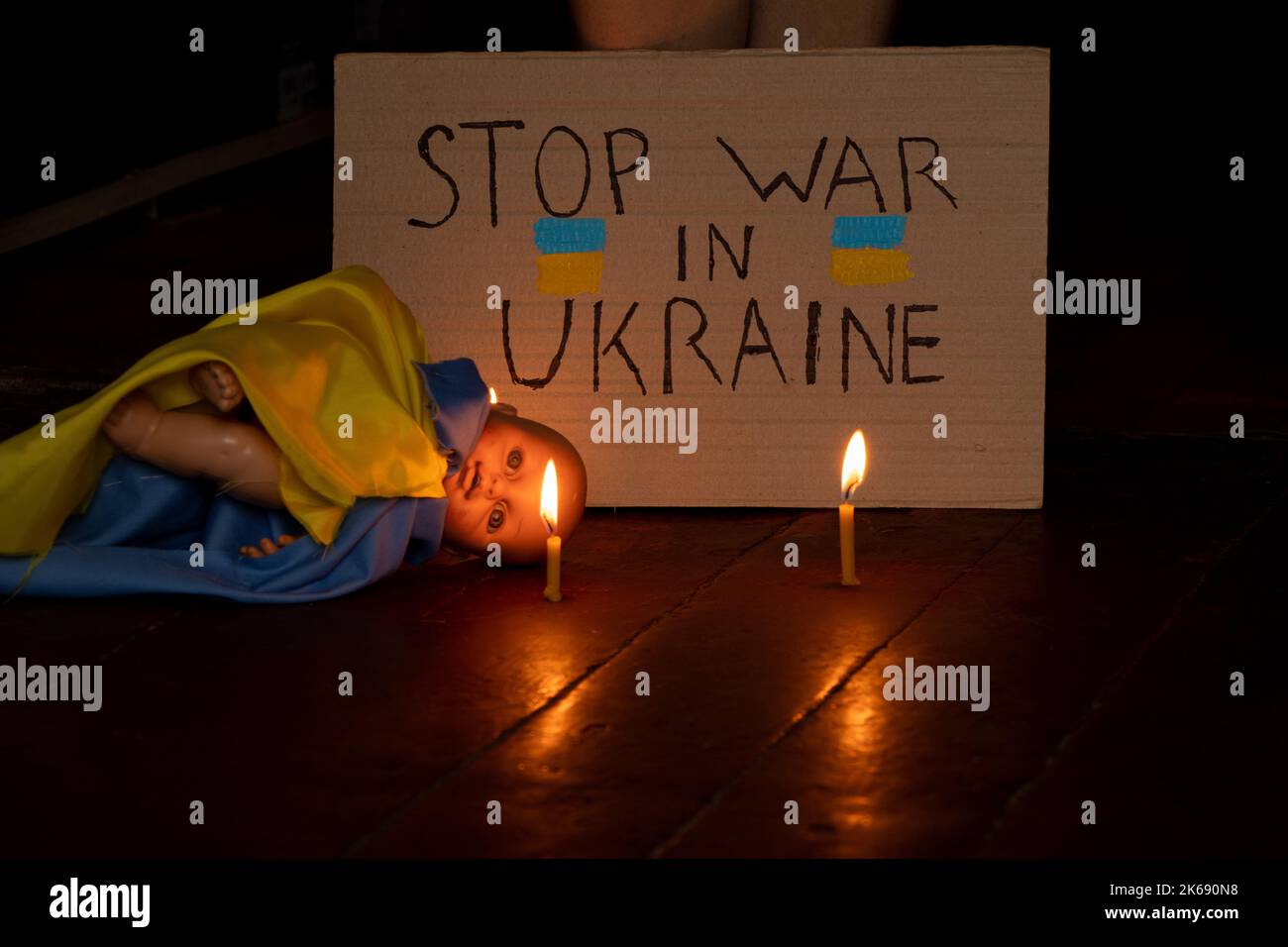 Poupée d'enfants avec le drapeau de l'Ukraine se trouve sur le plancher de la maison dans l'obscurité et à côté de est comme signe avec le texte arrêter la guerre en Ukraine, le deat Banque D'Images