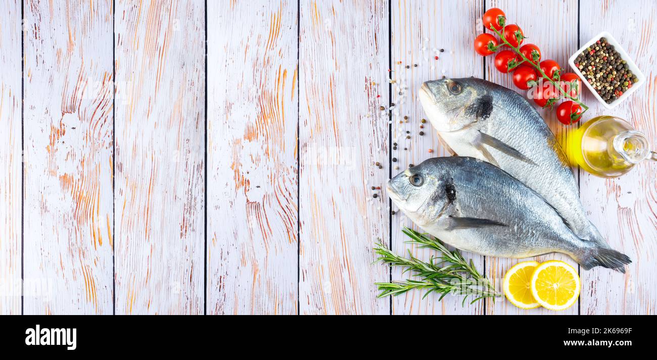 Dorado poisson sur fond en bois blanc avec espace de copie. Fruits de mer avec ingrédients pour la cuisson. Épices et légumes délicats. Bannière, en-tête, rétrogro Banque D'Images