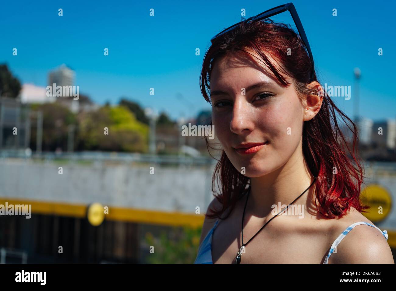 Un gros plan du visage d'une jeune femme aux cheveux rouges avec une expression satisfaite par temps ensoleillé. Copier l'espace. Orientation paysage. Banque D'Images