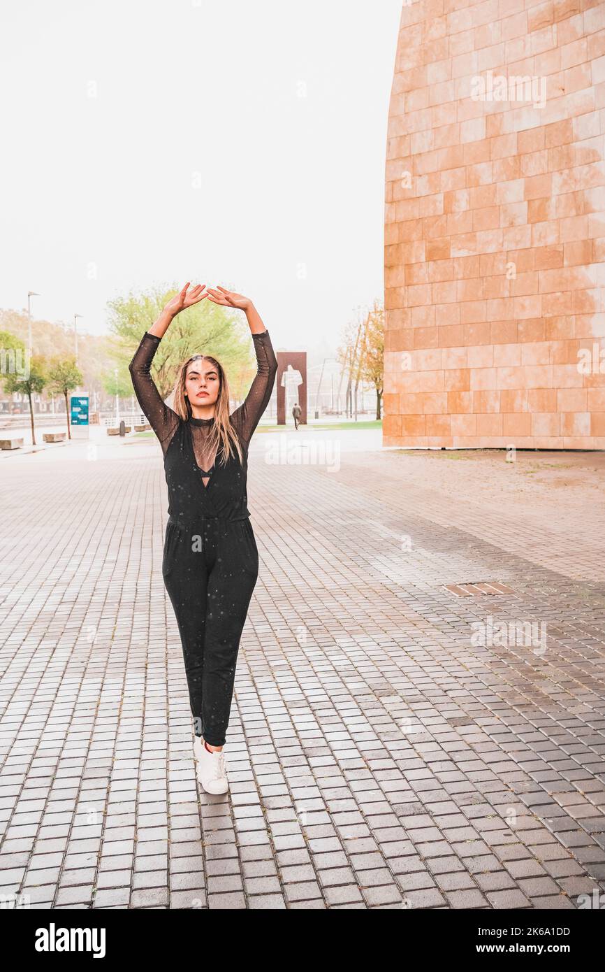 Jeune femme blonde vêtue de danse noire sous la pluie danse contemporaine de rue Banque D'Images