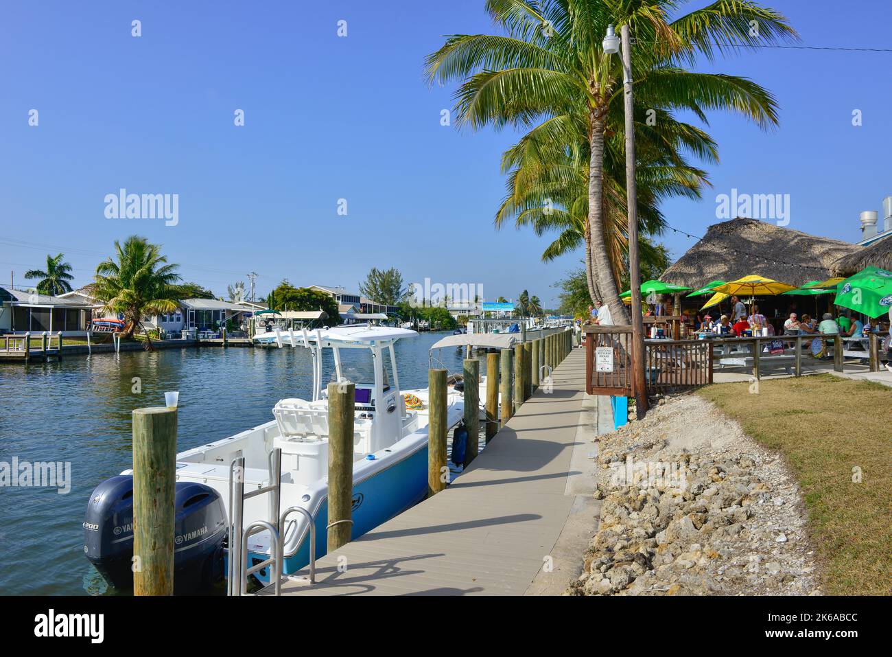 Vue sur les canaux avec des bateaux amarrés, à côté du restaurant et bar Phuzzy's Boat Shack avec toits de chaume et dîner en plein air à St. James City, Floride Banque D'Images