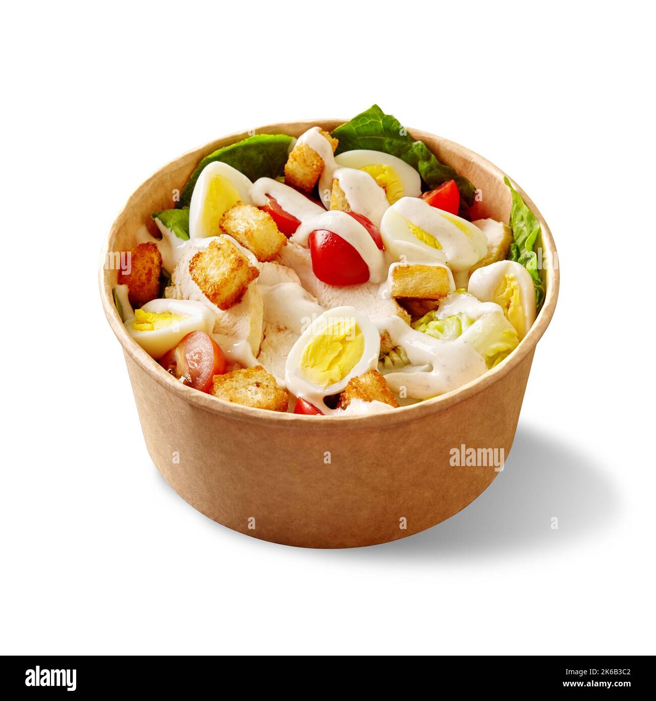 Salade César avec laitue, tomates cerises, œufs de caille, croûtons, poulet et sauce dans un bol en carton blanc Banque D'Images