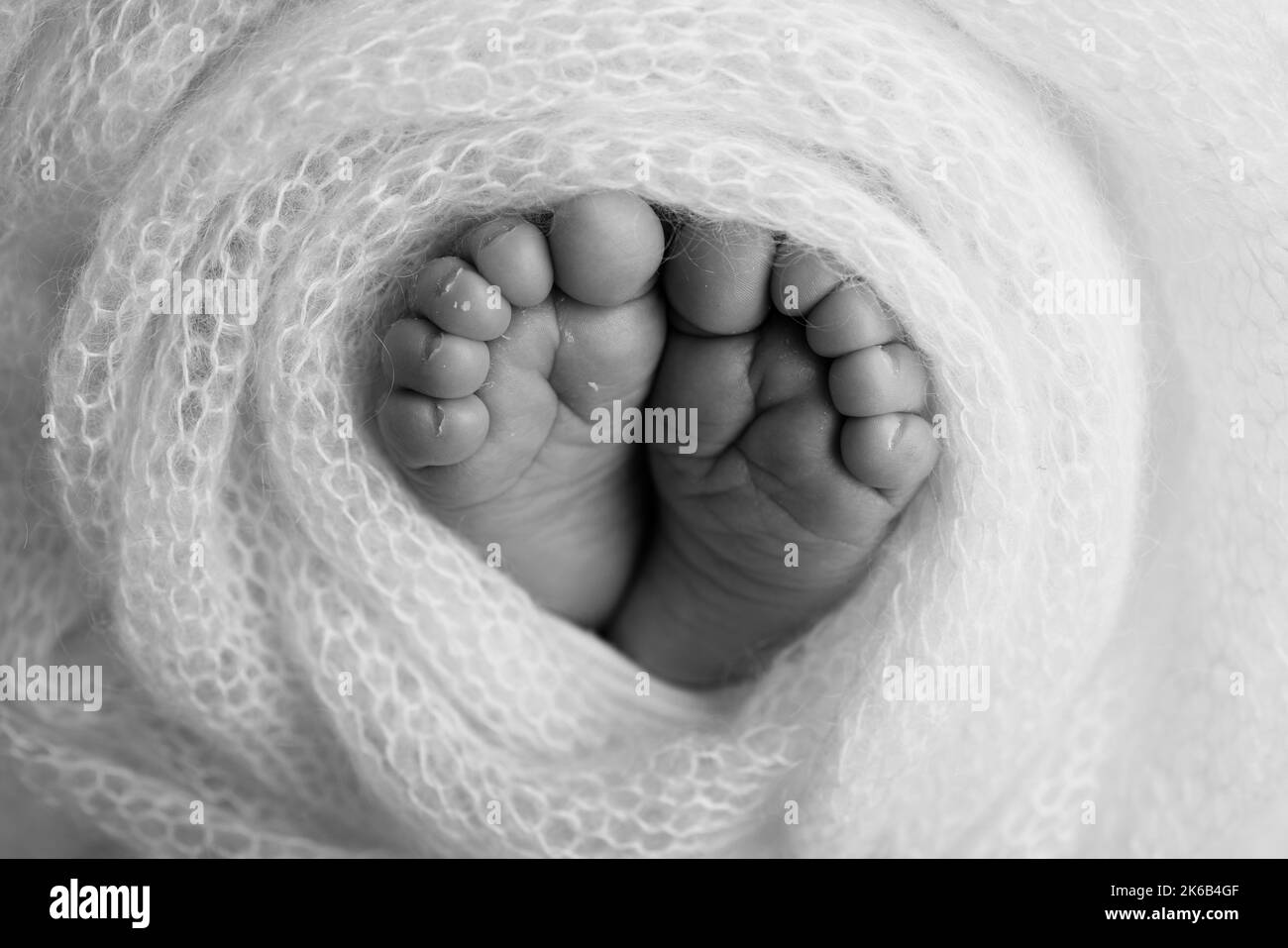 Pieds doux d'un nouveau-né dans une couverture en laine. Gros plan des orteils, des talons et des pieds d'un nouveau-né. Banque D'Images