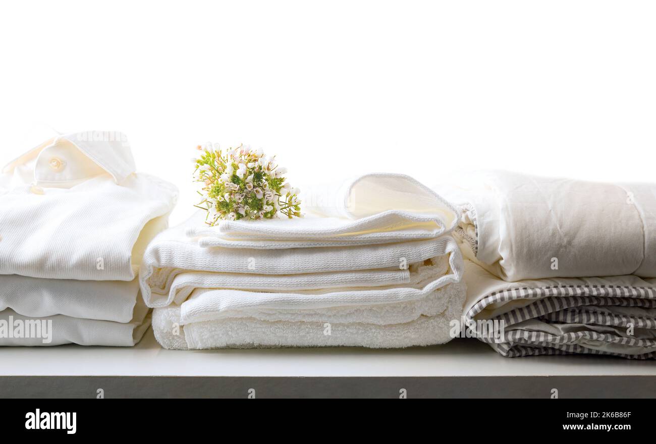 Blanc propre lit fraîchement lavé et plié et robe des vêtements sur table blanche et arrière-plan isolé. Vue avant. Composition horizontale. Banque D'Images