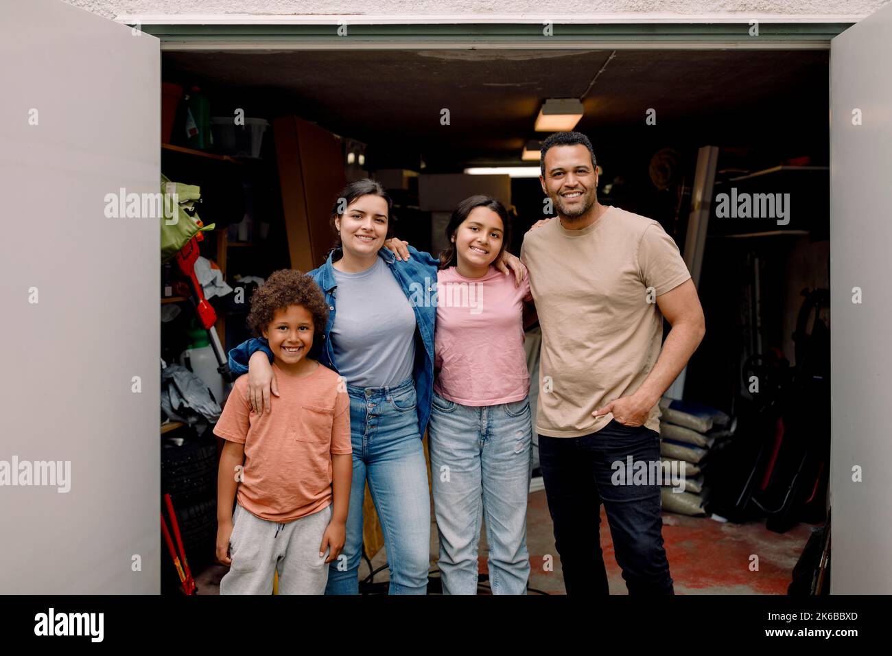 Portrait d'une famille multiraciale heureuse debout avec les bras autour de la salle de stockage extérieure Banque D'Images