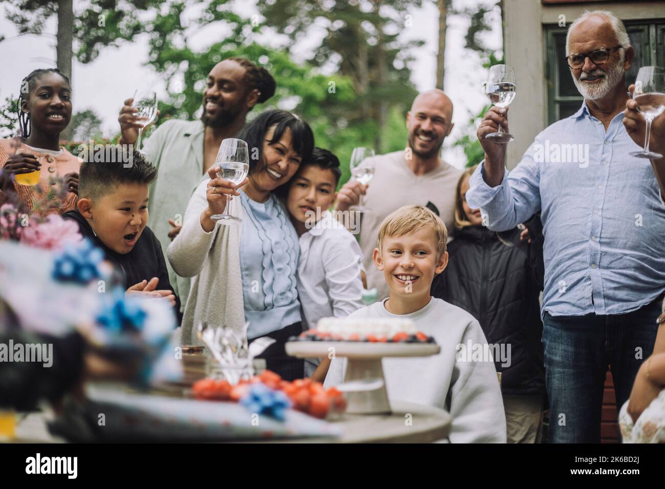 Famille de plusieurs générations qui applaudissent pour garçon lors de la fête d'anniversaire Banque D'Images
