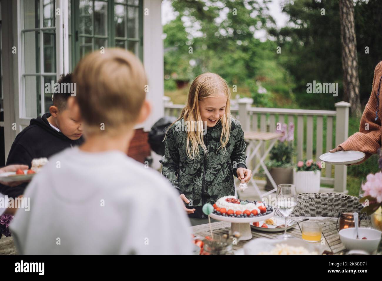 Fille coupant gâteau d'anniversaire en se tenant près de la table Banque D'Images
