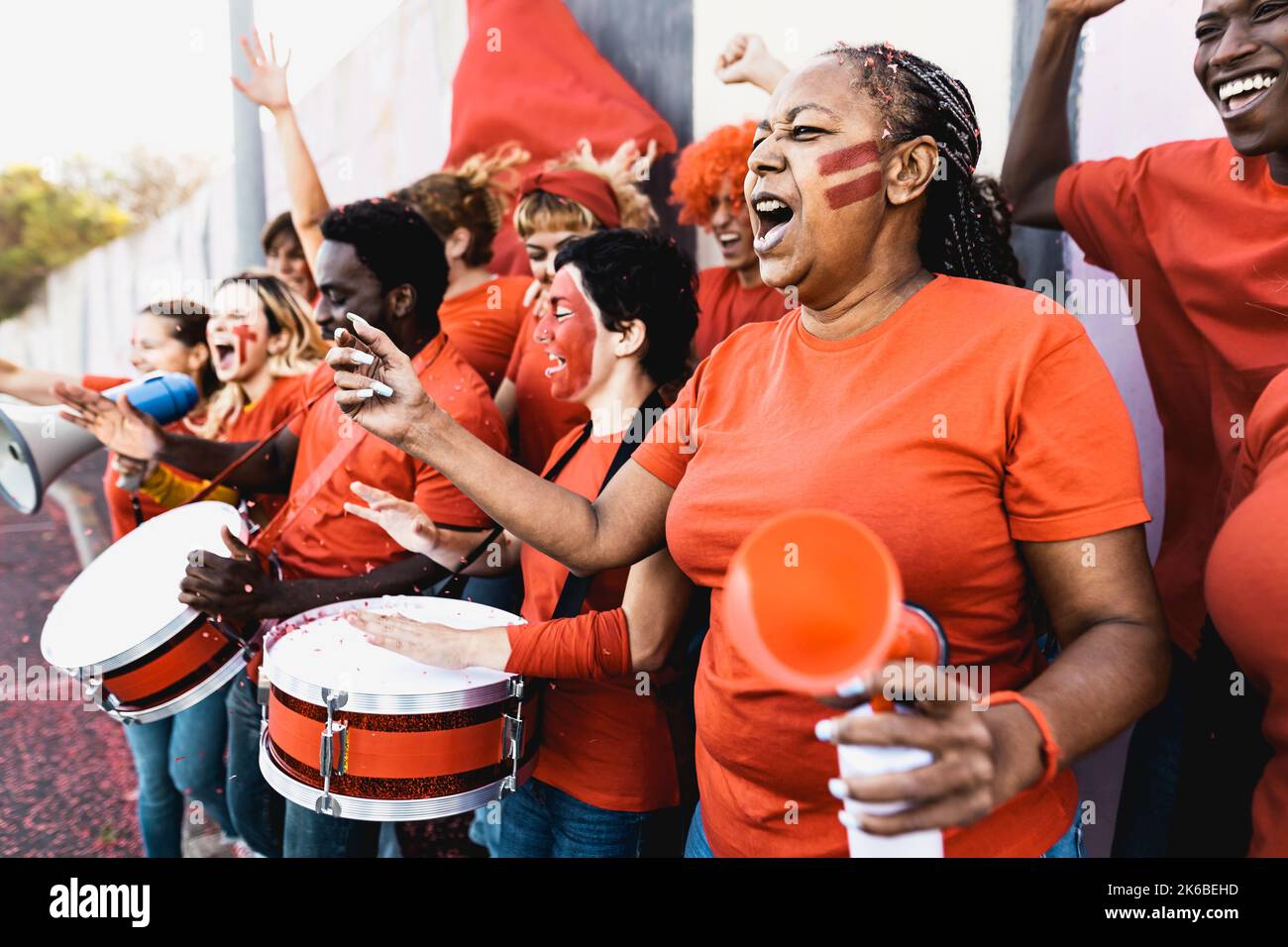 Les fans de football de foule s'exclatent en regardant un match de football au stade - des gens avec le visage et le tambour peints encourageant leur équipe Banque D'Images