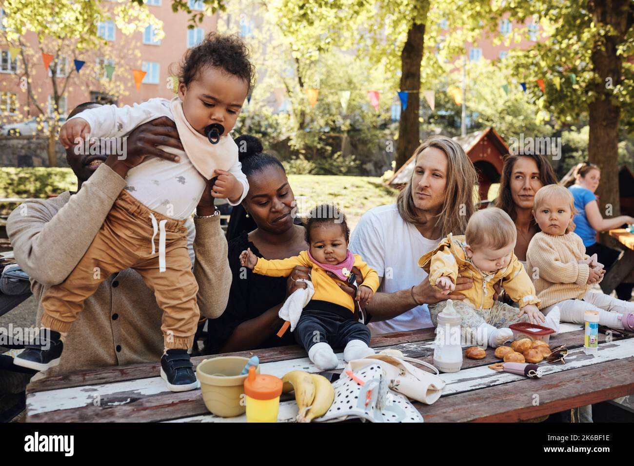 Des parents multiraciaux avec des enfants assis ensemble à la table de la maternelle Banque D'Images