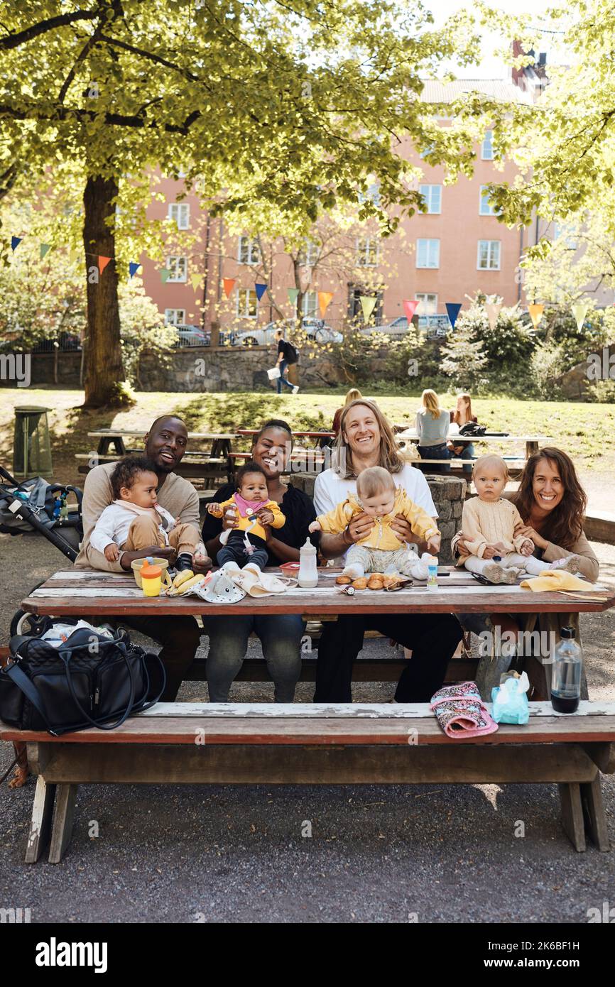 Portrait de parents multiraciaux heureux avec des enfants à la table de maternelle Banque D'Images