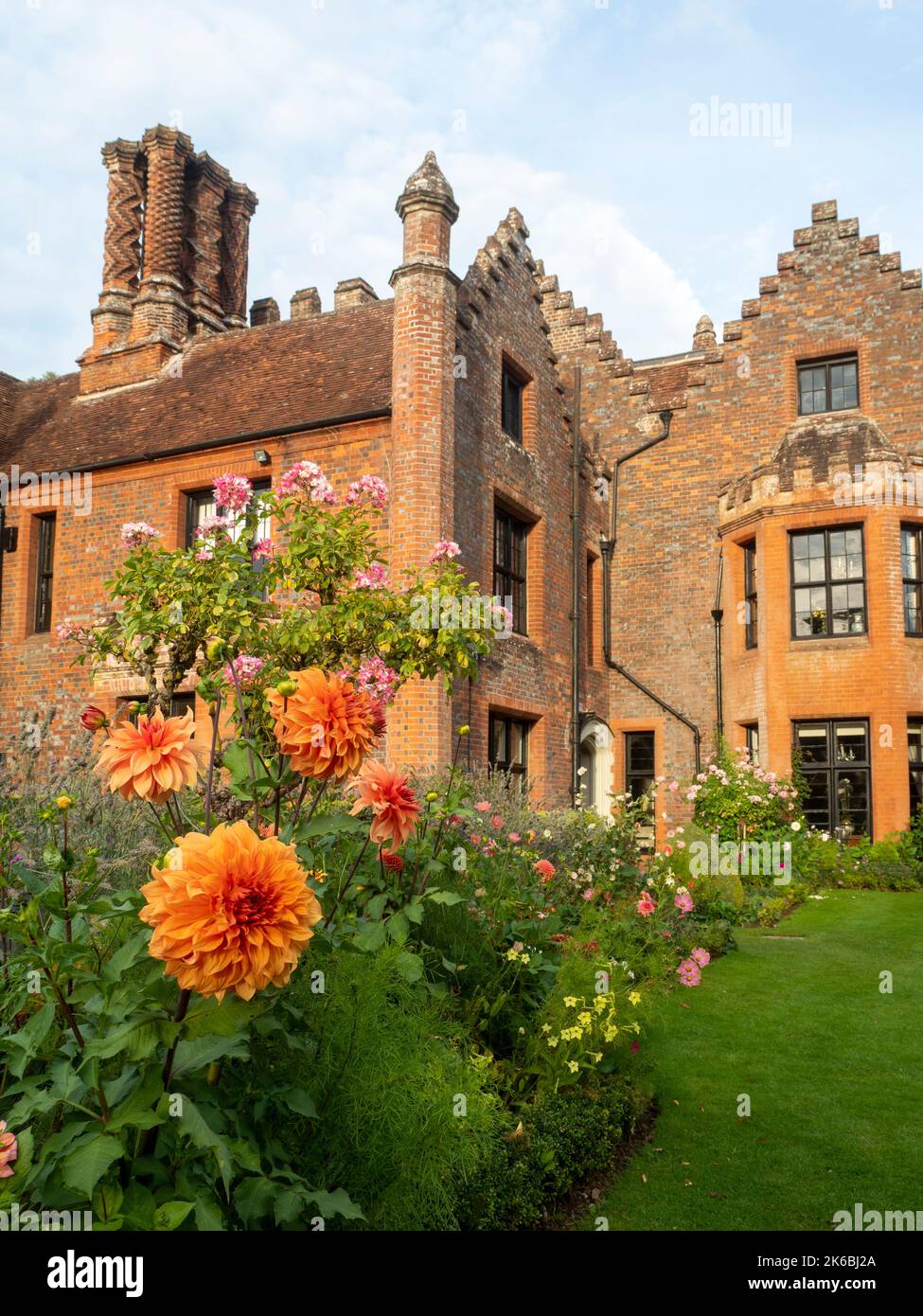 Chenies Manor et jardin entouré de Dahlias colorés en octobre. L'orange de bronze Dahlia 'Great Hercules' se blogne au-dessus du reste et Rosa 'Ballerina'. Banque D'Images