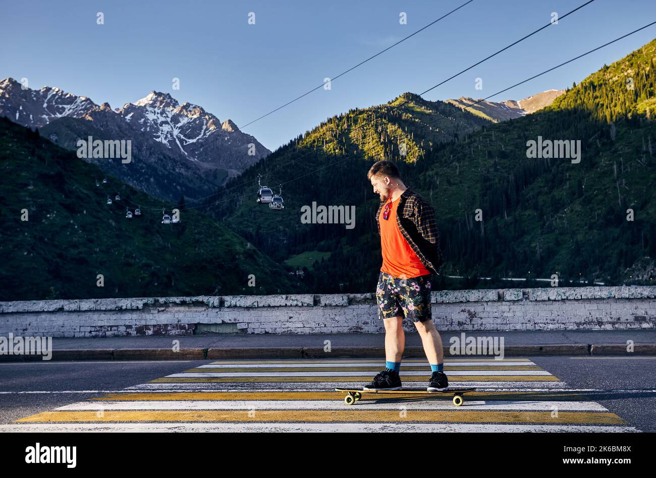 Homme barbu Skater voyage dans la route de montagne sur sa longue planche à Medeo Dum Almaty, Kazakhstan Banque D'Images