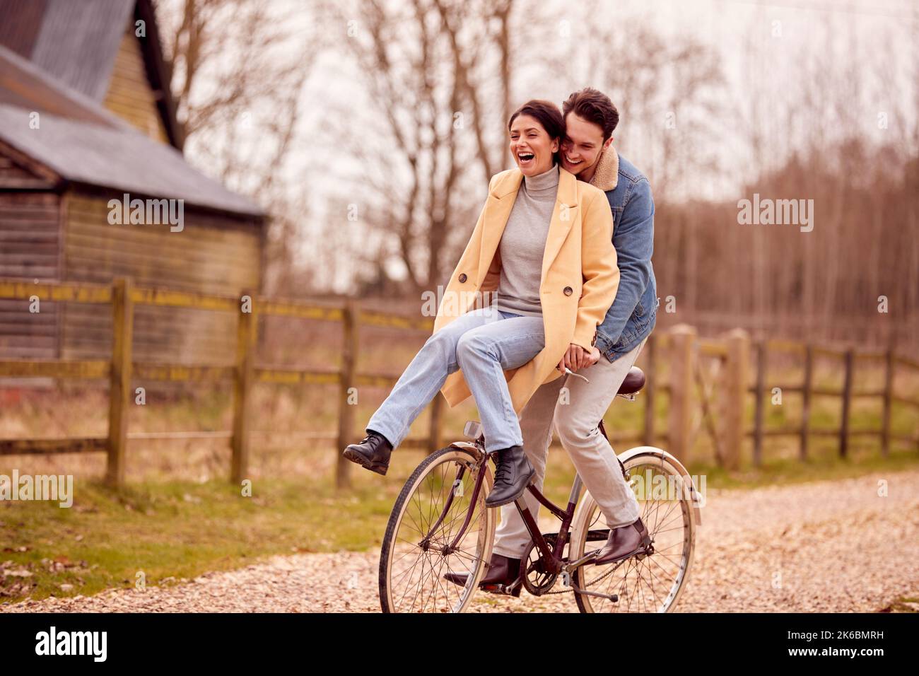 Couple transgenre aimant avec une femme à cheval sur le guidon du vélo en campagne d'automne ou d'hiver Banque D'Images