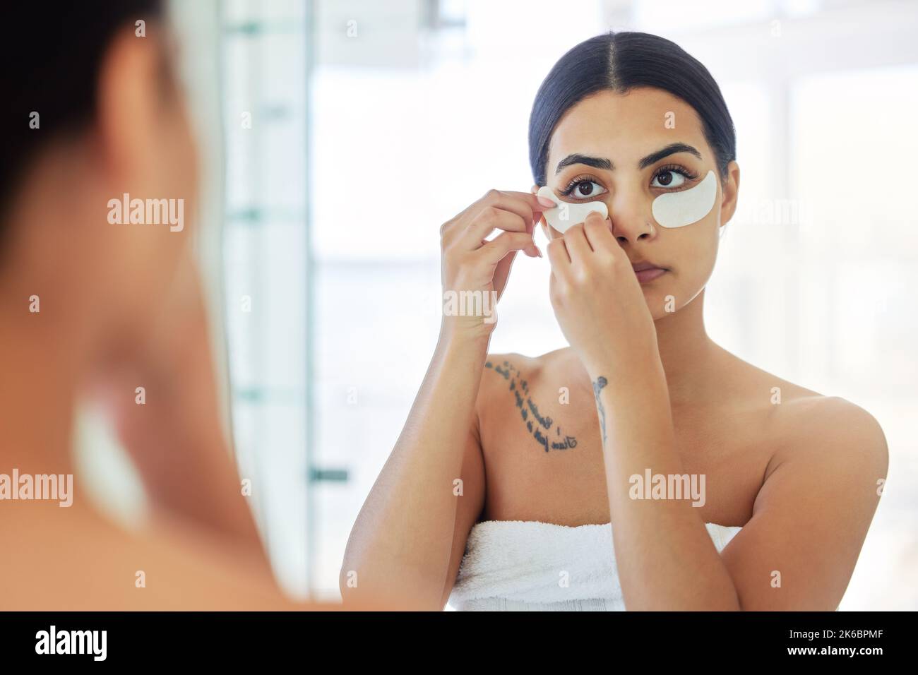 Juste un masque rapide. Une jeune femme utilisant des masques pour les yeux dans une salle de bains à la maison. Banque D'Images
