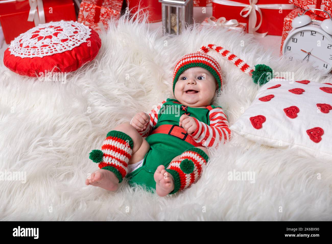 Nouveau-né bébé garçon habillé en costume gnome couché sur le tapis blanc de fourrure parmi les décorations de noël. Photo de Noël du bébé en casquette à tête trippée. Nouvel an co Banque D'Images