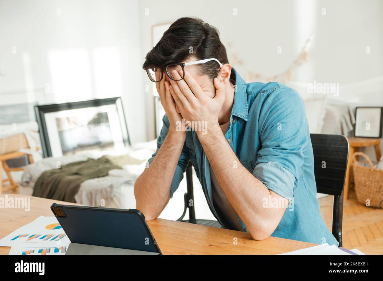 Contrarié jeune homme caucasien payant des factures se sentant stressé en raison de problèmes financiers. Le pigiste a perdu son argent et ne peut pas payer ses impôts. Financement Banque D'Images