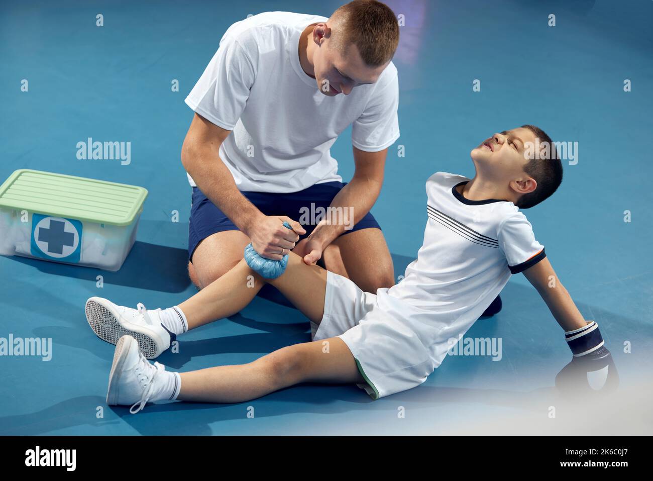 Entraîneur personnel, entraîneur d'équipe fournit les premiers soins à un athlète avec une blessure de jambe. Entraînement de boxe dans la salle de gym. Sport, médecine, étudier Banque D'Images