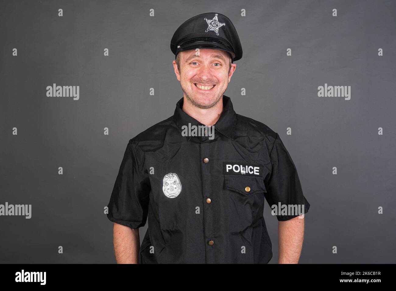 Portrait d'un homme de race blanche portant un costume de police sur fond gris de studio Banque D'Images