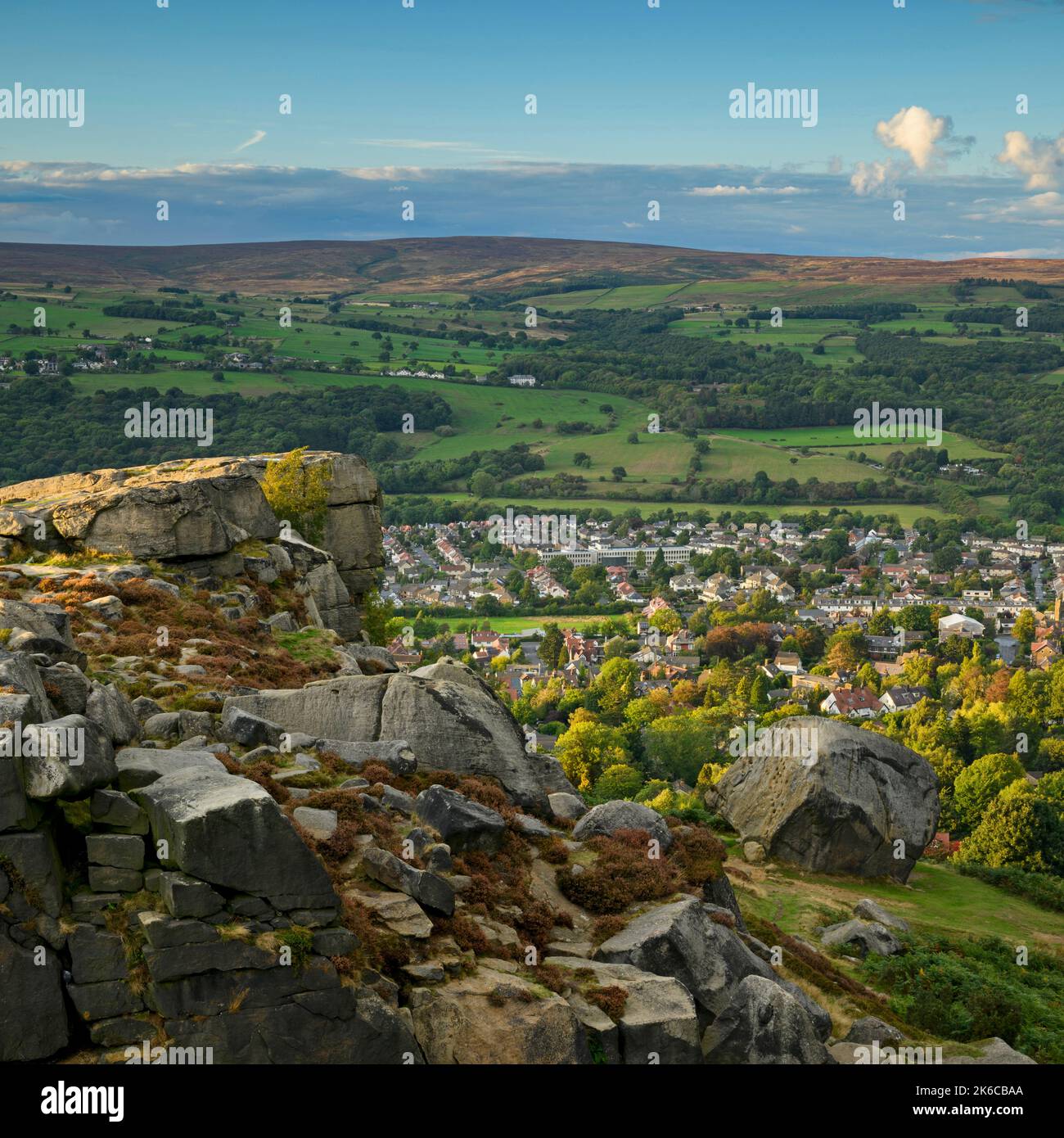 The Cow & Calf Rocks (vue pittoresque sur le village de la vallée de Wharfe, crag de haut douves, ciel bleu) - Ilkley Moor, West Yorkshire, Angleterre. Banque D'Images