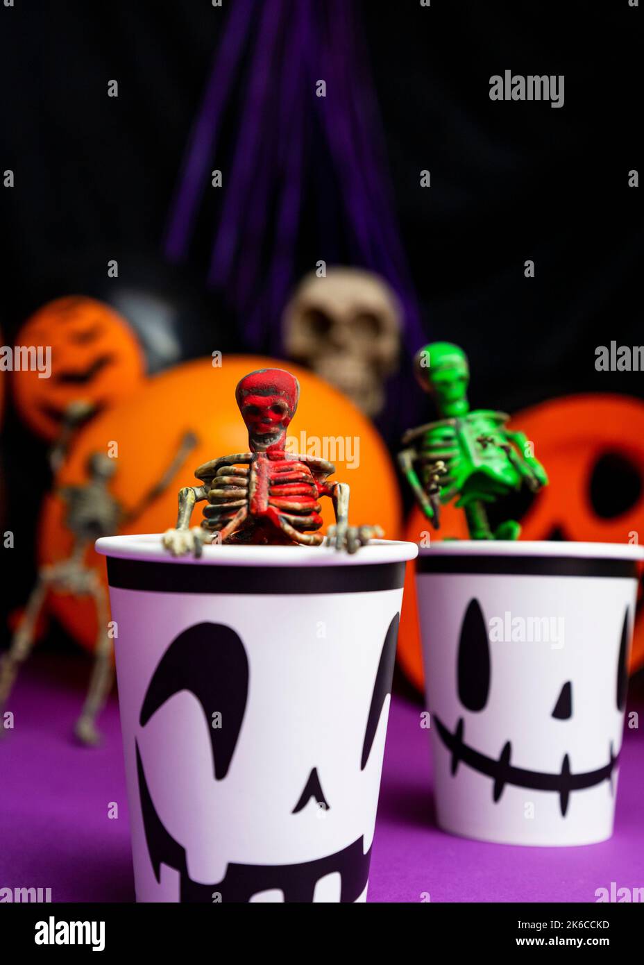 Fête d'Halloween. Squelettes sortant de la tasse avec ballons et crâne en arrière-plan Banque D'Images
