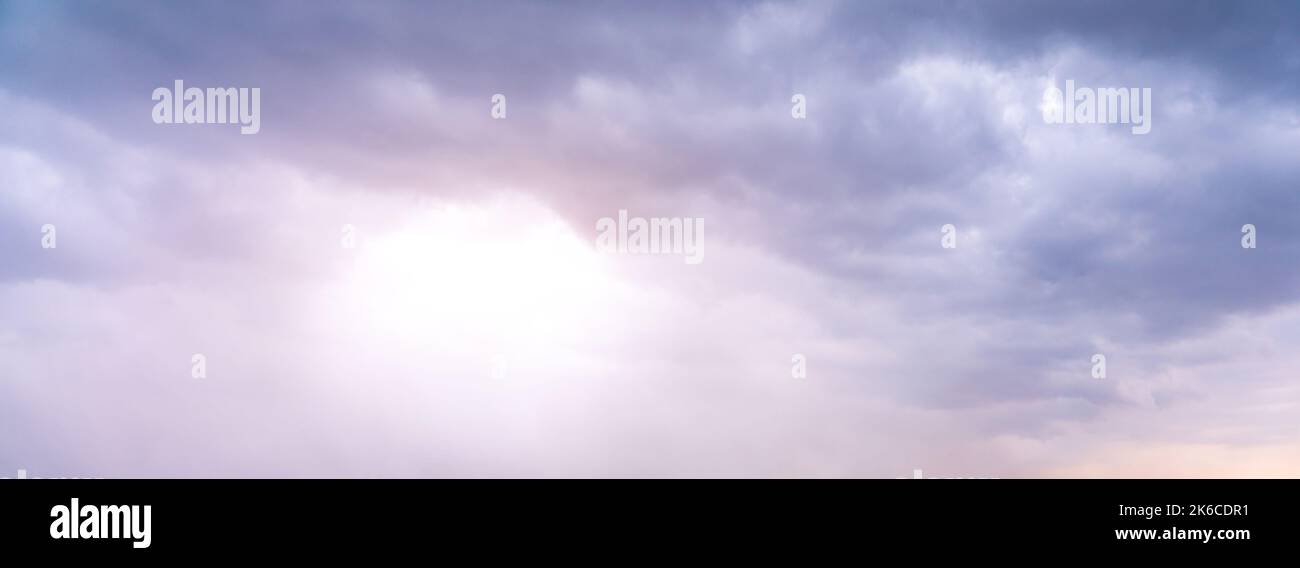 Le soleil brille à travers les nuages gris et sombres Banque D'Images