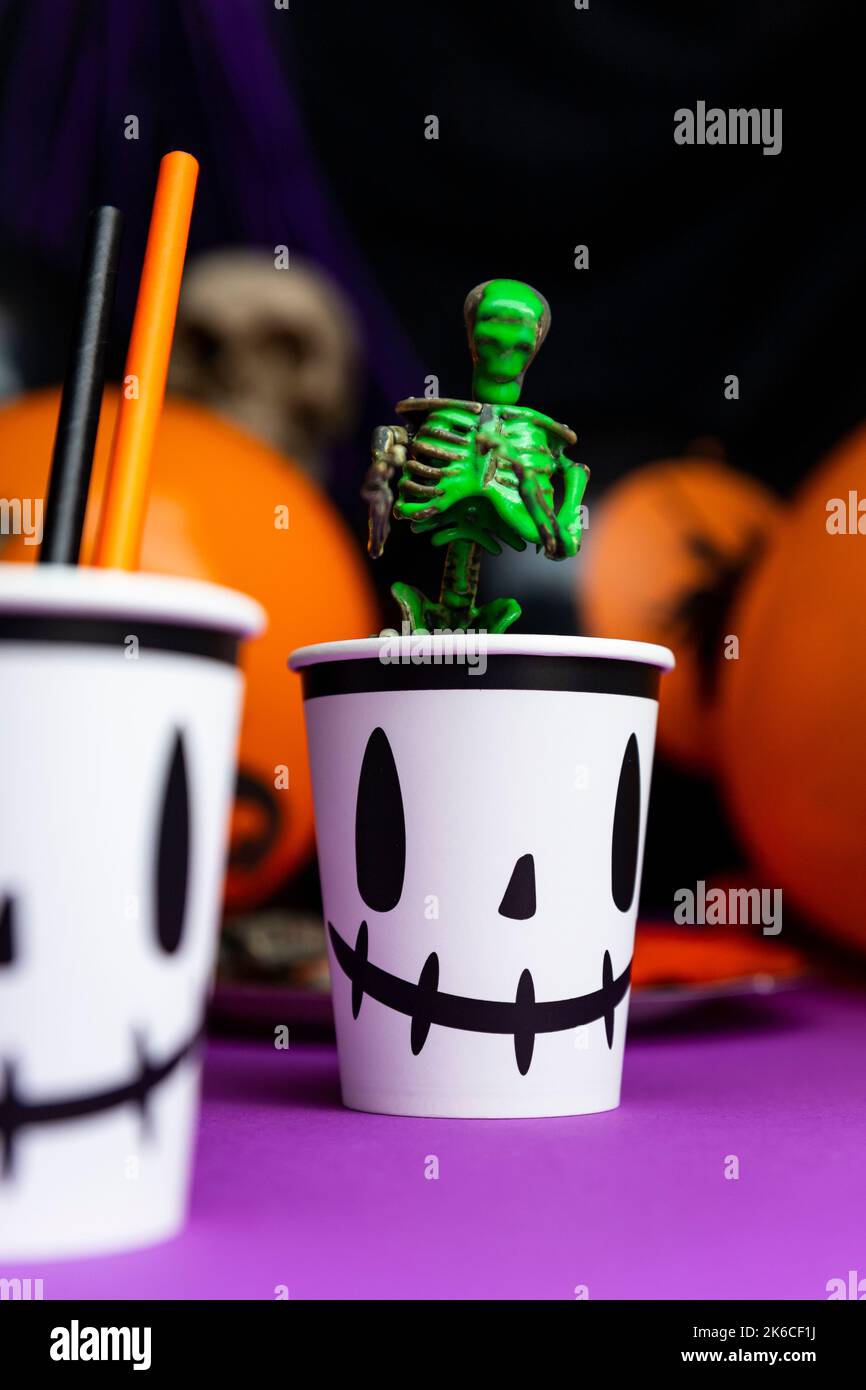 Fête d'Halloween. Squelette recouvert de vert citron vert sortant de la tasse avec des ballons et crâne en arrière-plan Banque D'Images