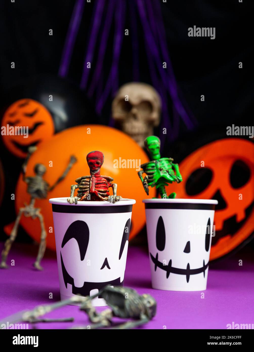 Fête d'Halloween. Squelettes sortant de la tasse avec ballons et crâne en arrière-plan Banque D'Images