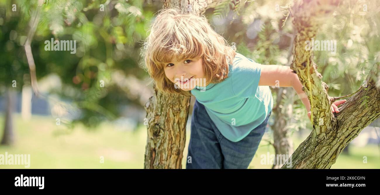 Grimper les arbres est toujours amusant. Arbre de montée enfant de garçon actif. Amusement d'enfance. En été. Affiche horizontale. En-tête de bannière Web, espace de copie. Banque D'Images