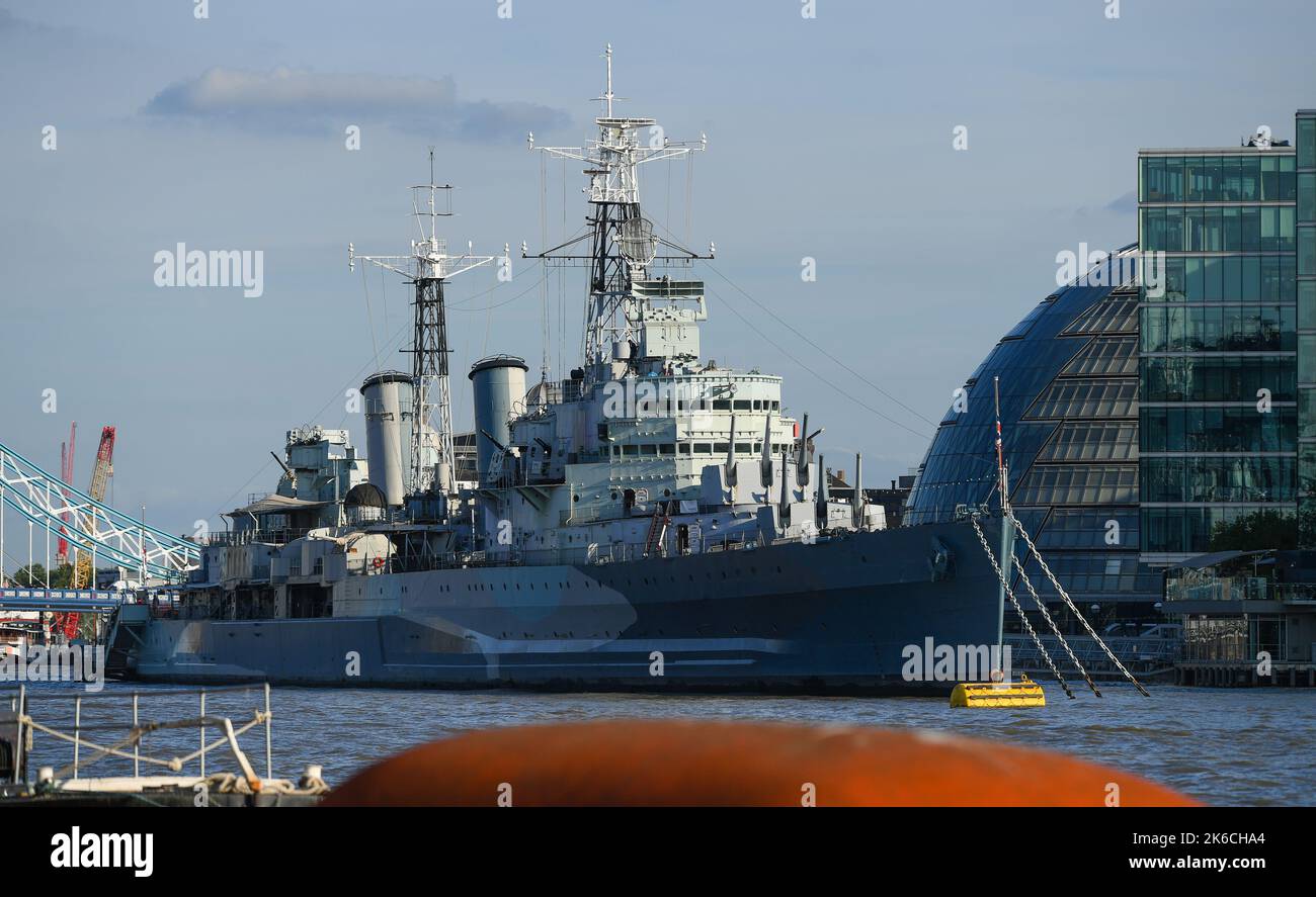 Une vue téléobjectif du HMS Belfast amarré sur la Tamise avec des immeubles de bureaux modernes derrière à Londres en Angleterre. Banque D'Images