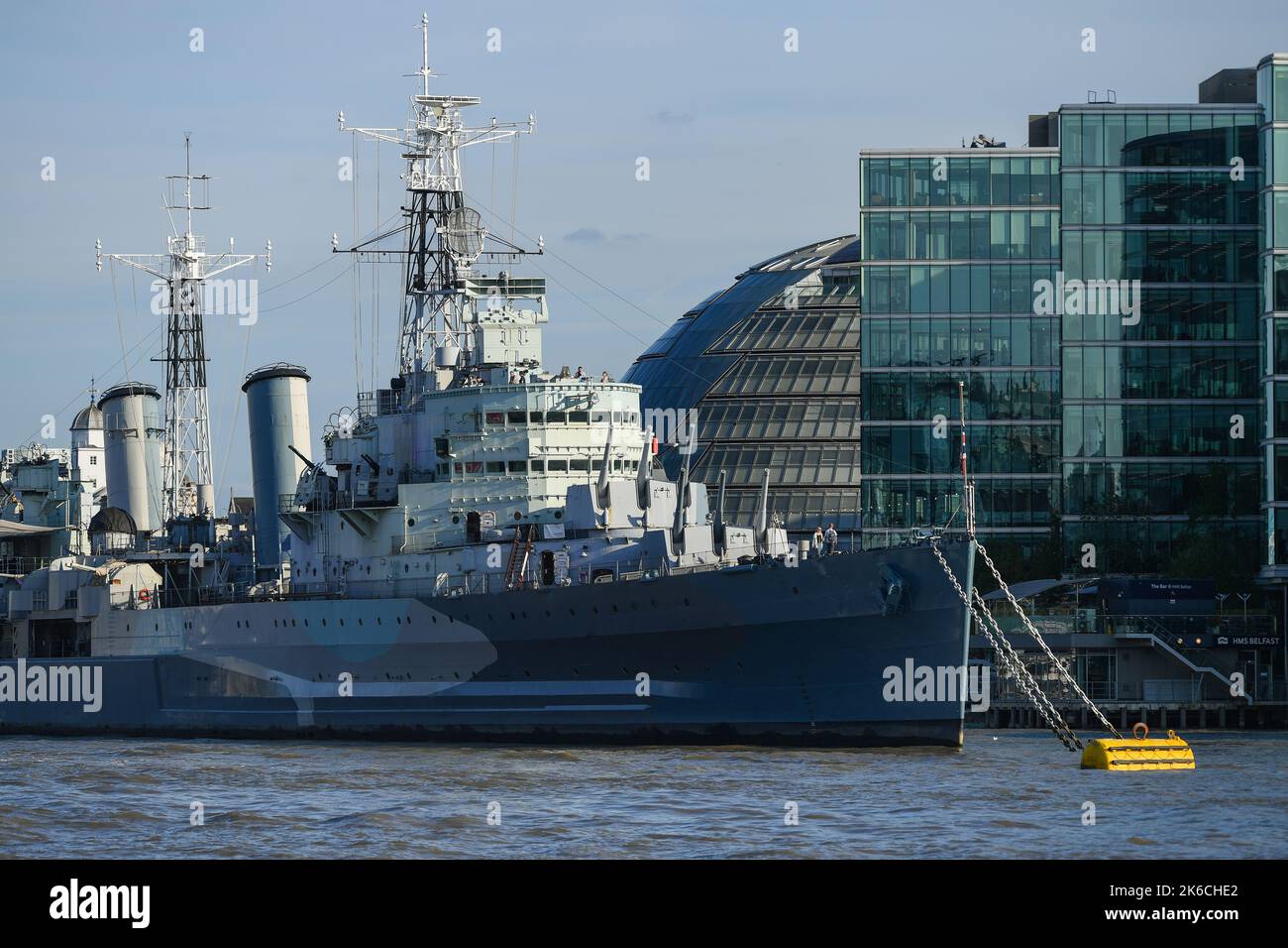 Une vue téléobjectif du HMS Belfast amarré sur la Tamise avec des immeubles de bureaux modernes derrière à Londres en Angleterre. Banque D'Images