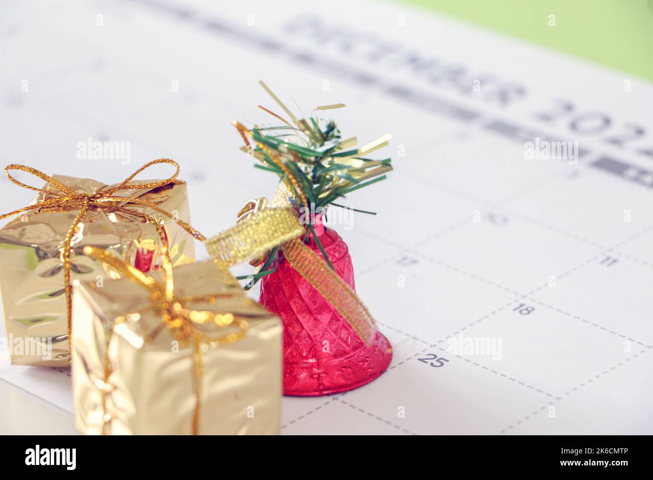 Décoration de Noël, petits cadeaux dorés et cloche rouge brillant marquant le 25th décembre sur le calendrier, concept de Noël Banque D'Images