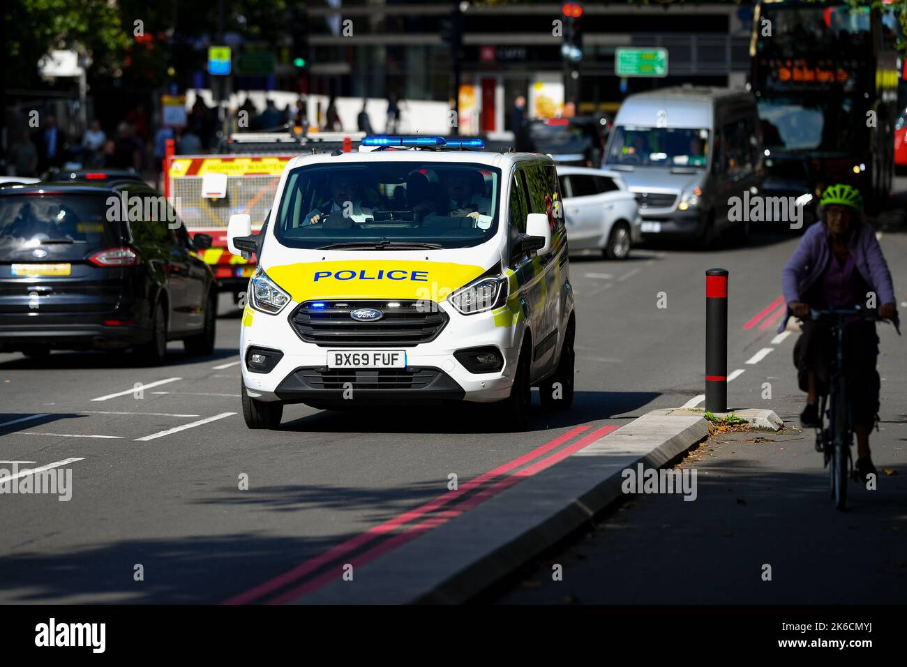 Image d'un minibus de police sur un appel d'urgence en traversant la circulation sur la route du palais de Lambeth, Londres, Royaume-Uni, à côté d'une piste cyclable au soleil du début de l'après-midi. Banque D'Images