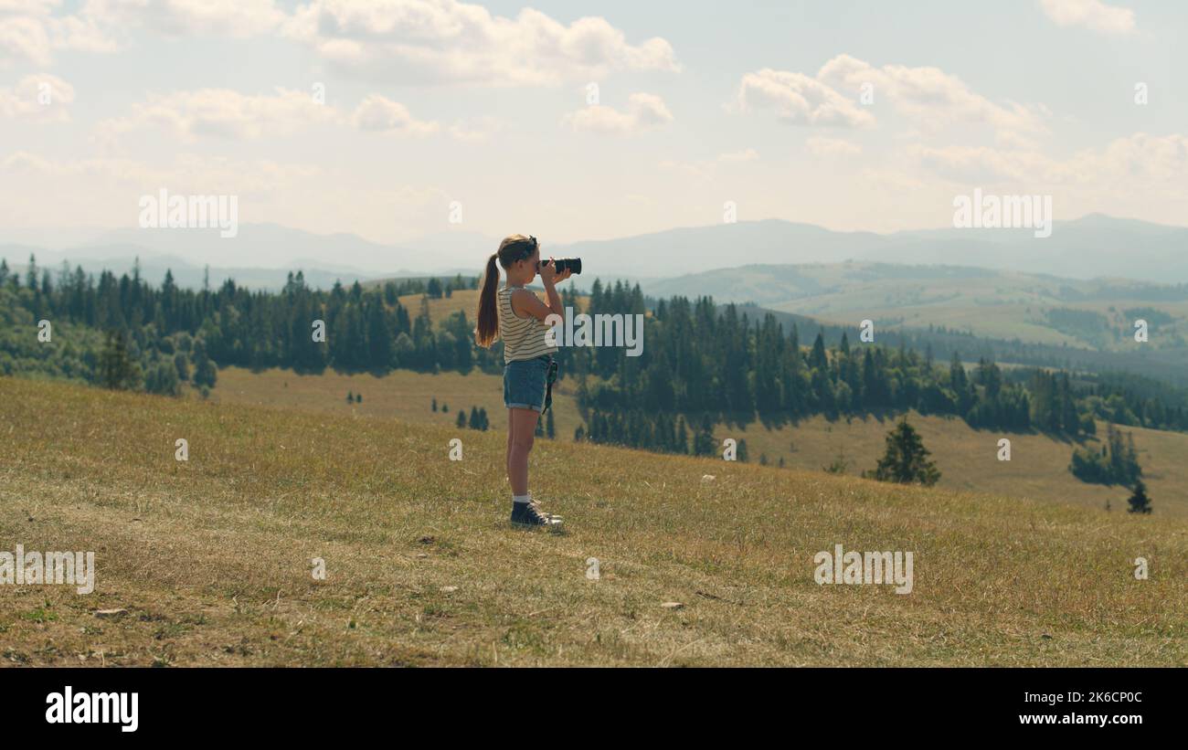 Jeune photographe qui photographie un paysage sur une colline verdoyante, prend des photos de la nature. Fille remplissant le portefeuille avec des images étonnantes, passant du temps de loisirs en plein air. Banque D'Images