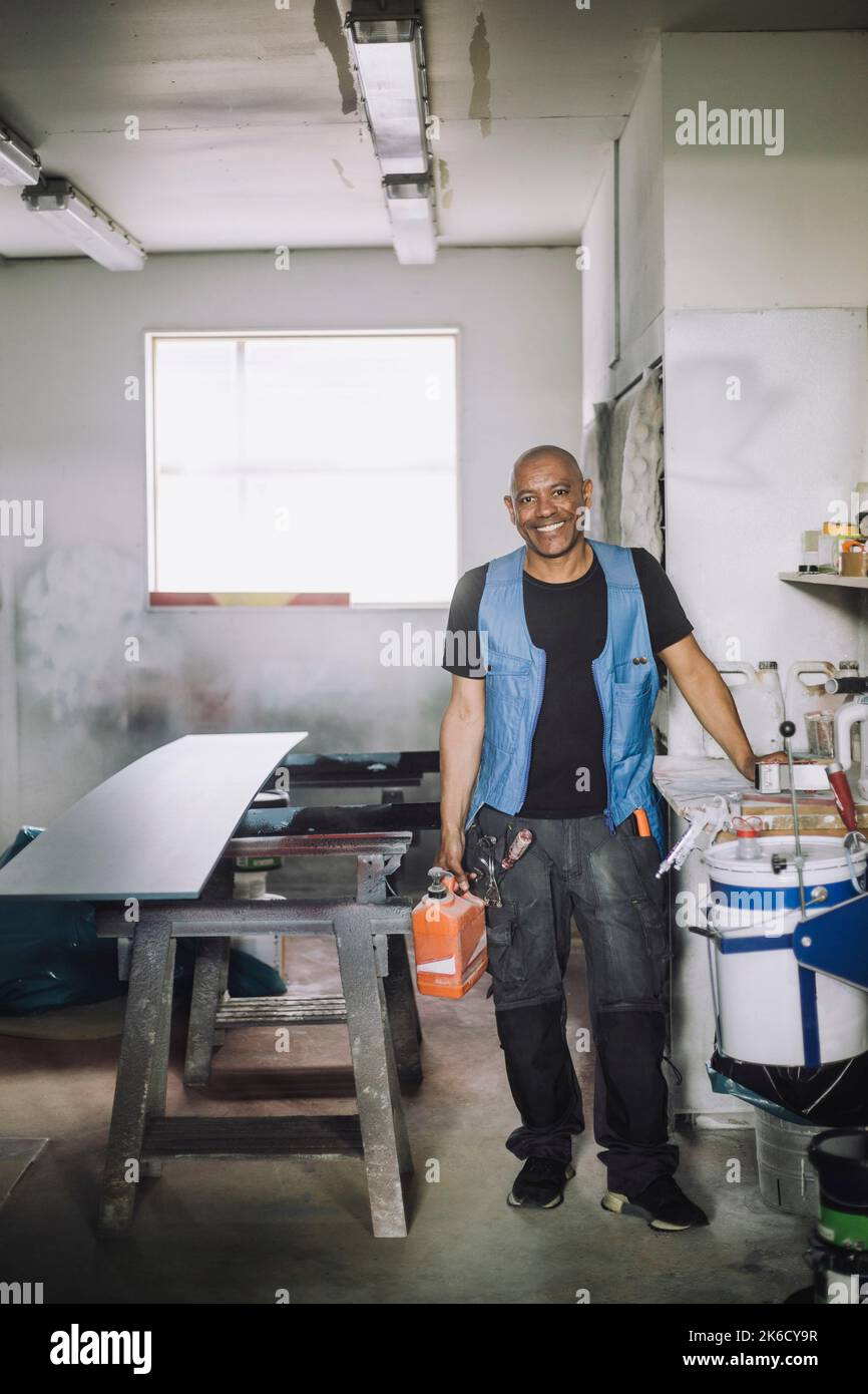 Portrait complet d'un peintre masculin souriant en atelier Banque D'Images