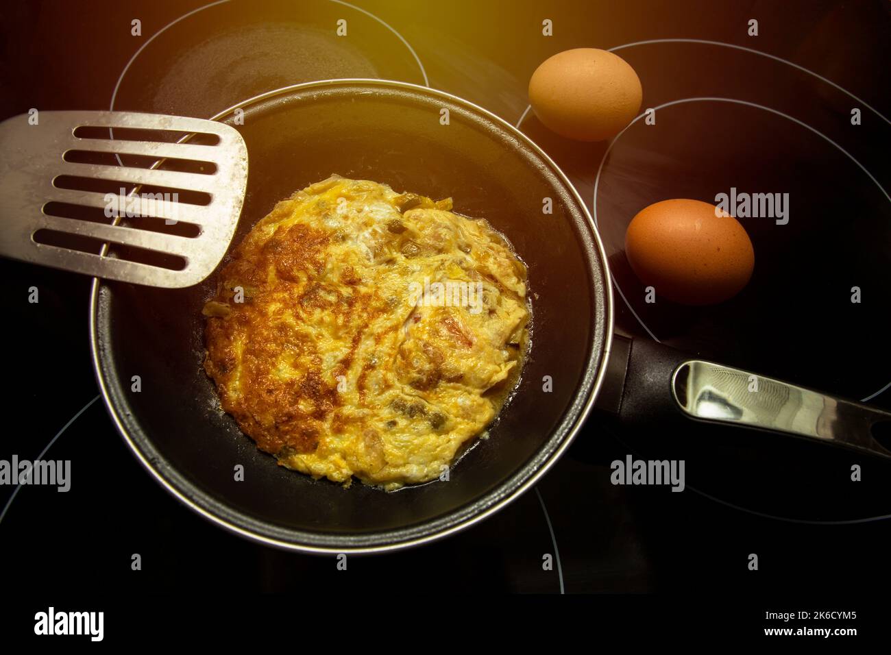 vue de dessus de l'omelette étant faite dans une poêle en métal et deux oeufs non cuits Banque D'Images