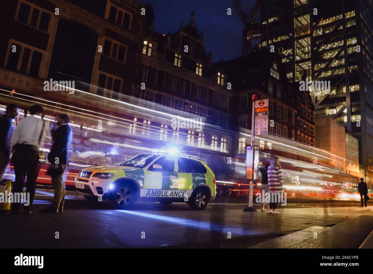 Une longue exposition d'une rue avec des personnes marchant et une voiture d'ambulance la nuit Banque D'Images