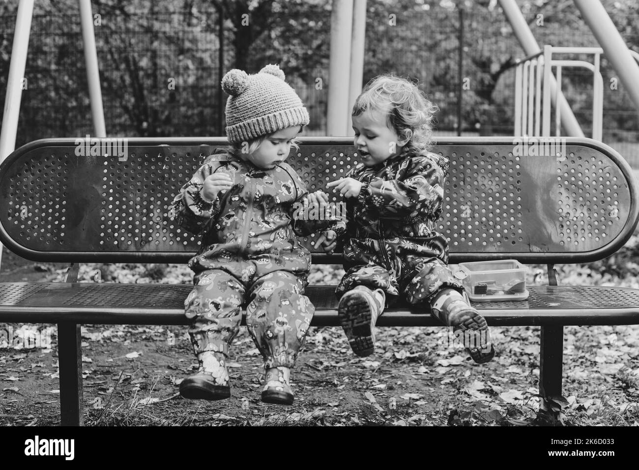Deux enfants, filles, tout-petits, assis sur un banc de parc Banque D'Images